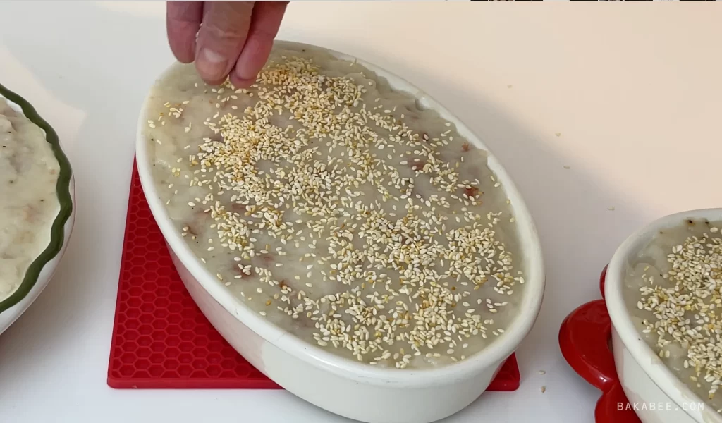 Sprinkle toasted white sesame seeds onto Chinese turnip cakes