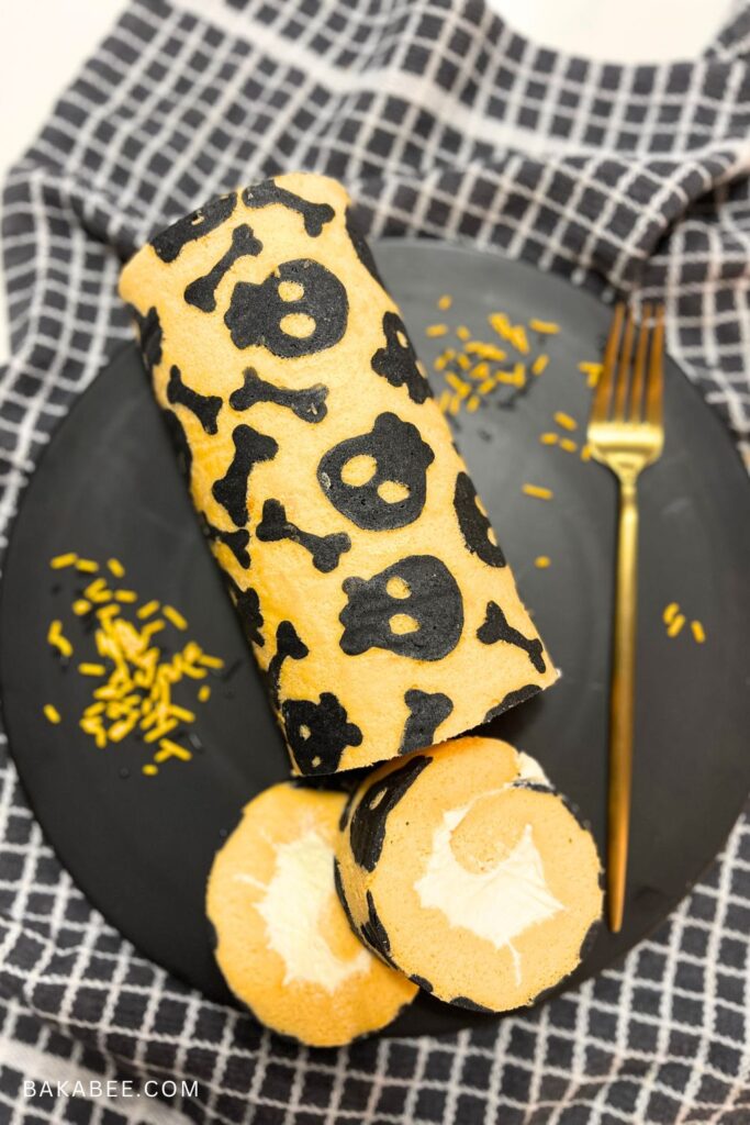 Halloween Pattern Swiss roll on a black plate with a gold fork and some orange and black sprinkles