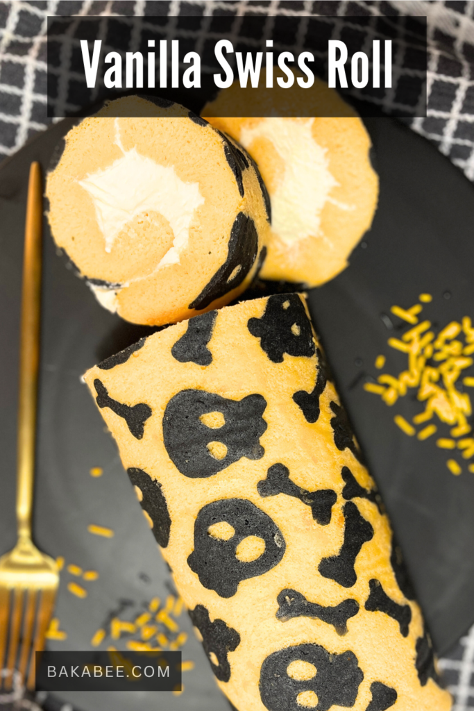 an orange roll cake with skeleton and bones design serves on a black plate with a gold fork