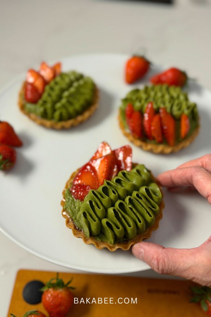 holding a matcha strawberry tart