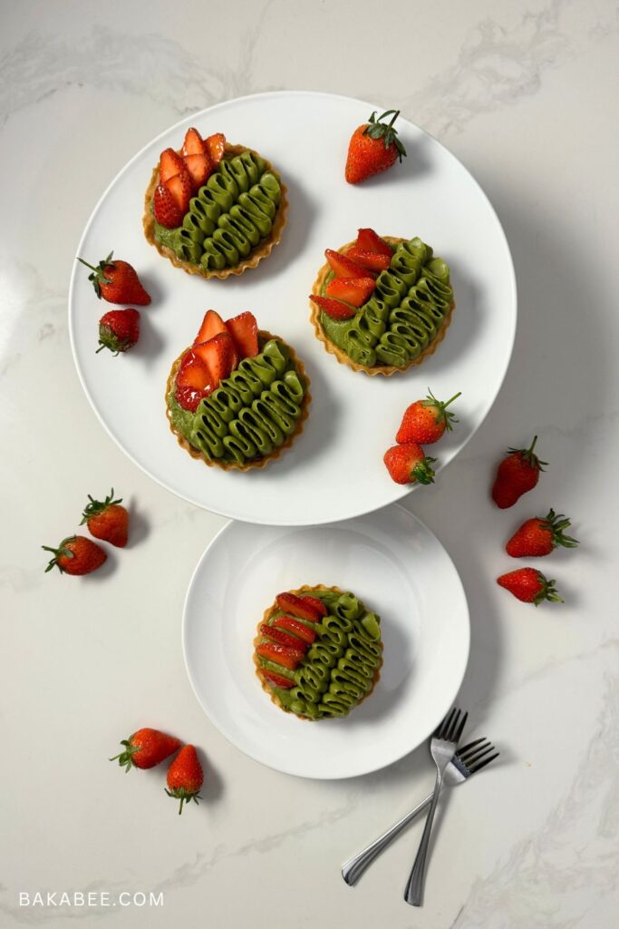 four matcha strawberry tarts and some fresh strawberries