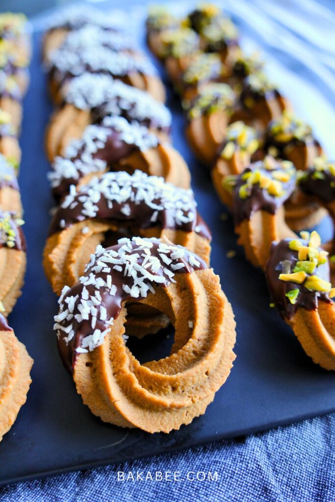 coffee Viennese whirl biscuits are served on a black plate and decorated with dark chocolate and desiccated coconut
