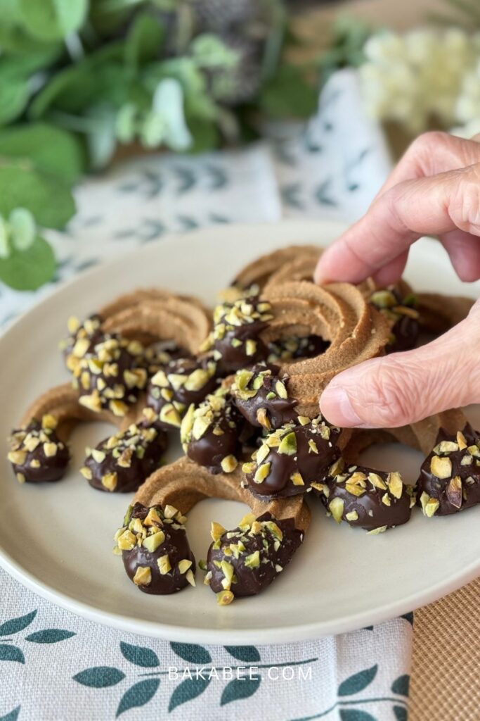 pick up a coffee Viennese whirl biscuit decorated with dark chocolate and chopped pistachio
