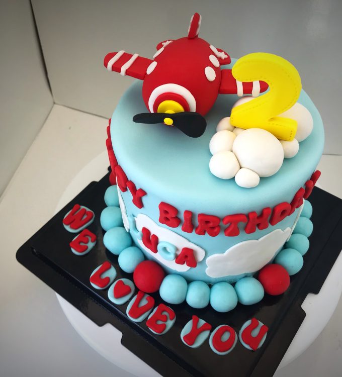 Chocolate cake with chocolate buttercream frosting, decorated with handcrafted cute aeroplane, clouds and messages